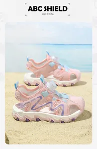 Detailed view of pink girls' closed-toe beach sandals on a sunny beach background