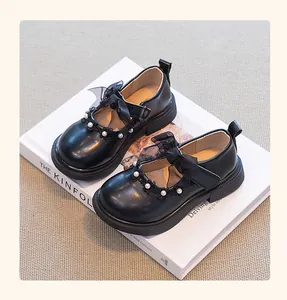Detalle de zapatos de princesa negros para niñas con lazo y perlas.