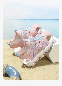 Close-up of pink children's sports sandals with a twist-knob closure on the beach.