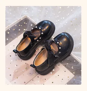 Detalle de zapatos de princesa negros para niñas con perlas y lazos de malla fina