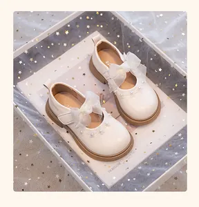 Vista detallada de zapatos de princesa blancos para niña con lazo de organza y perla.