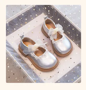 Vista detallada de zapatos de princesa plateados para niña con lazo blanco y perlas