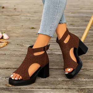 Macro detail of brown chunky heel Roman sandals featuring intricate hollow floral cutouts