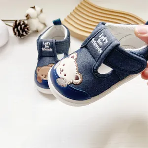 Detailaufnahme blauer Denim-Lauflernschuhe für Babys mit süßem gesticktem Bärenmotiv.
