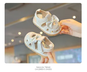 Détail de sandales blanches pour bébé fille avec nœud, dentelle et semelle souple.