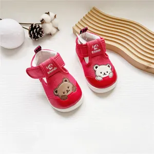 Detail von roten Lauflernschuhen für Kleinkinder mit Bärenstickerei und Klettverschluss