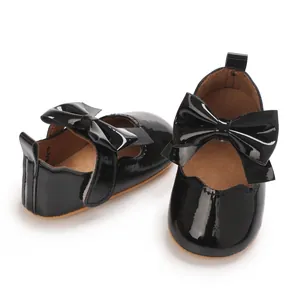 Vue détaillée de chaussures de bébé en cuir verni noir avec nœud et bande auto-agrippante
