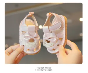 Détail des sandales roses pour bébé fille avec nœud en dentelle et semelle souple.