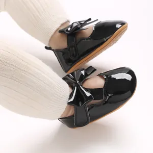 Gros plan sur des chaussures de princesse pour bébé en cuir verni noir avec nœuds élégants