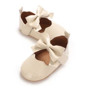 Vue détaillée de chaussures Mary Jane beige pour bébé avec grands nœuds vernis.