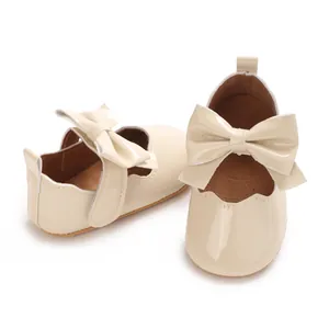 Détail de chaussures de marche vernies beiges pour bébé fille avec un grand nœud