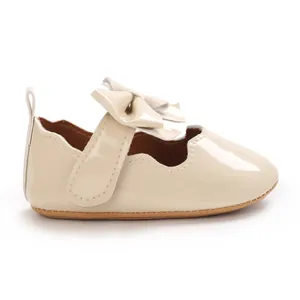 Détail de profil d'une chaussure beige brillante pour bébé fille avec un nœud décoratif.