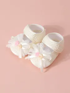 Detailed macro view of cream lace baby girl princess shoes with ribbon bow and flowers
