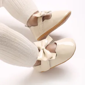 Gros plan de chaussures de princesse pour bébé en cuir verni crème avec un joli nœud.