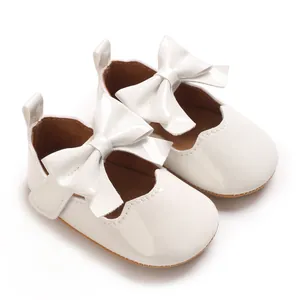 Détail de chaussures de princesse blanches pour bébé avec nœud et bordure ondulée