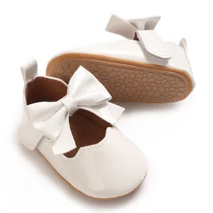 Détail de chaussures de princesse pour bébé fille en cuir verni blanc avec nœud