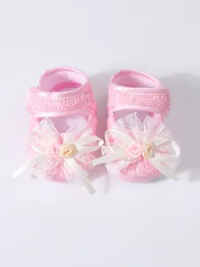 Elegant pink lace baby princess shoes with delicate white ribbon bow and floral details