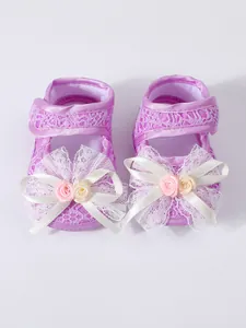 Detailed view of purple baby girl princess shoes with lace bows and soft soles