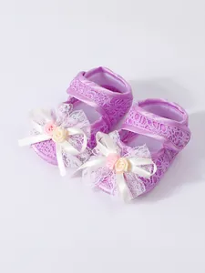 Detailed macro view of purple lace baby girl pre-walker shoes with white floral bows.