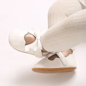 Gros plan de chaussures de bébé en cuir verni blanc avec un joli nœud et un velcro