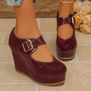Detail of burgundy patent leather Mary Jane shoes with platform wedge heel and buckle.