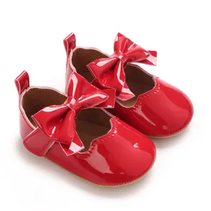 Vue détaillée des chaussures de bébé pour fille en cuir verni rouge vif avec un nœud mignon.