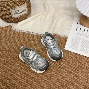 Vue détaillée de baskets en mesh gris respirant pour enfants sur un tapis rustique