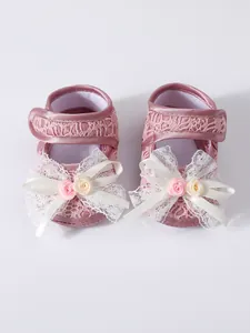 Close-up detail of adorable pink baby girl princess shoes with lace and ribbon bow decorations