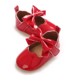 Détail de chaussures de princesse rouges en cuir verni pour bébé avec un grand nœud