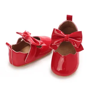Gros plan de chaussures princesse rouges en cuir verni pour bébé fille avec nœud