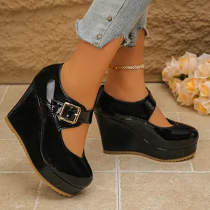 Close-up detail shot of black patent leather Mary Jane platform wedge shoes worn by model