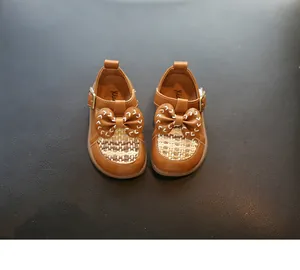 Nahaufnahme brauner Kleinkinderschuhe aus Leder mit Schleife und gewebtem Detail