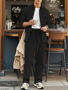 Men's casual black corduroy shirt and trousers set worn by a model in a cafe setting