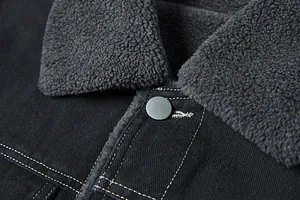 Dettaglio ravvicinato di una giacca di jeans da uomo con colletto in sherpa e cuciture