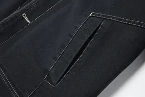Dettaglio delle cuciture a contrasto bianche sulla tasca di una giacca di jeans nera