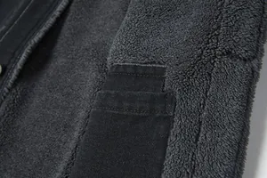 Primo piano dettagliato della calda fodera in pile grigio di una giacca in denim nero.