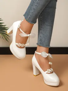 Vue détaillée de talons hauts blancs avec accents floraux et chaînes de perles