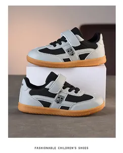 Vue latérale de baskets enfant gris et noir avec semelles en gomme marron sur support blanc