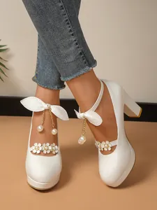 Détail de chaussures de princesse blanches à talons avec perles et nœud