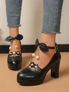 Détail de chaussures à talons hauts noirs avec pompons en perles et brides à fleurs
