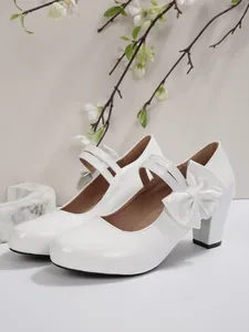 Détail de chaussures Mary Jane blanches en cuir verni à talon carré avec nœud décoratif