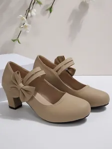 Zapatos beige de tacón ancho con lazo decorativo y punta redonda estilo Mary Jane.