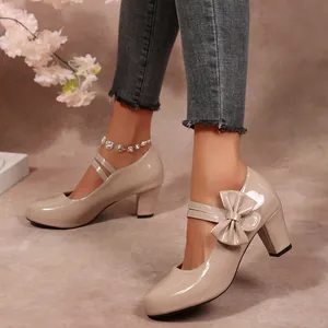 Gros plan de chaussures Mary Jane beiges brillantes à talons blocs et nœud décoratif