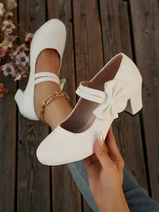 Detalle de zapatos blancos de punta redonda con un lazo y un cierre de velcro seguro