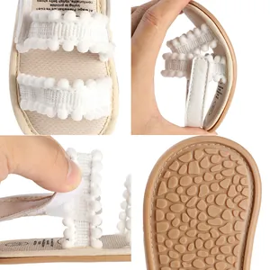 Detailansicht von Babysandalen mit flexibler Sohle und weichem Pompon-Besatz