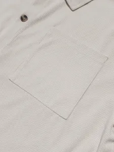 Close-up detail of a beige men's corduroy shirt featuring a chest pocket and button