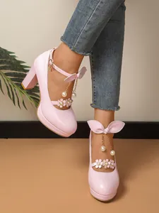 Vue détaillée d'escarpins roses à talons épais avec nœuds papillon et breloques en perles