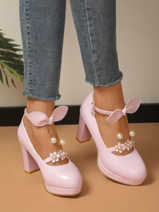 Détail de talons plateformes roses style princesse avec des nœuds et des perles décoratifs.