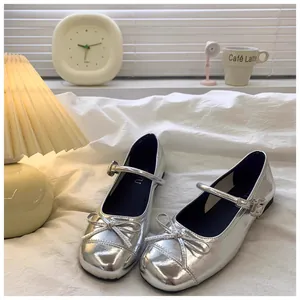 Gedetailleerd beeld van stijlvolle zilveren Mary Jane schoenen met strikjes voor meisjes.