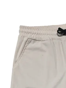 Close-up detail of off-white corduroy pants featuring an elastic waistband and drawstring